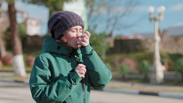 Portrait of a young woman experiences an asthmatic attack while walking on the street, uses a nebulizer. Outdoor