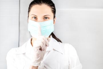 nurse in medical mask gesture and asking to be quiet with finger on lips