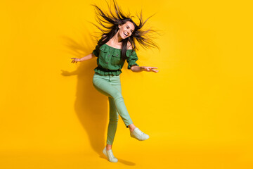 Fototapeta na wymiar Photo portrait full body view of woman kicking laughing with flowing hair isolated on vivid yellow colored background