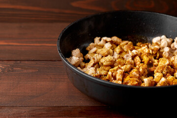 finely chopped chicken fillet fried in curry spices for salad preparation, ingredients on a plate on a wooden background