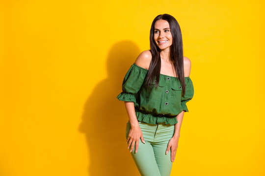 Photo portrait of beautiful brunette in green clothes smiling cheerfully looking empty space isolated on vivid yellow color background