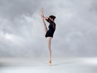 Fototapeta na wymiar Dancer in vertical split on a cloud background 
