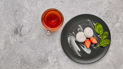 Homemade marshmallow on a gray plate with strawberries and a green leaf. Marshmallow with a cup of tea. Homemade marshmallow. The concept of tea drinking. The view from the top.