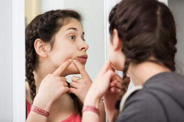 Young teenage girl cleaning face skin alone at home