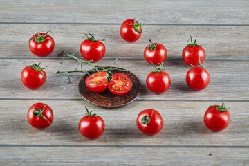 Bunch of fresh juicy tomatoes and slices of tomato on wooden table