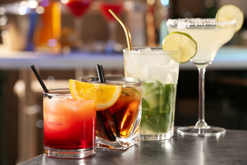 Different delicious cocktails on grey table in bar