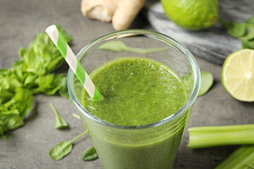 Green juice and fresh ingredients on grey table, closeup