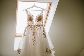 A bride dress wearing on hanger against the window at home