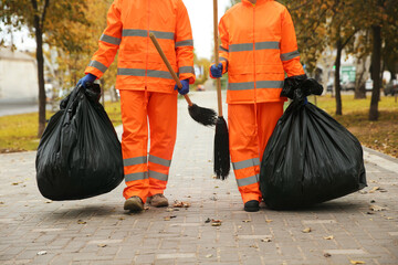 Street cleaner with brooms and garbage bags outdoors on autumn day