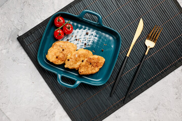 Traditional chicken schnitzel and cherry tomatoes on a gray concrete background. Chicken cutlets...