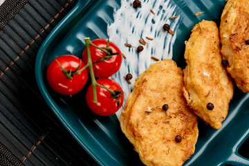 Traditional chicken schnitzel and cherry tomatoes on a gray concrete background. Chicken cutlets...