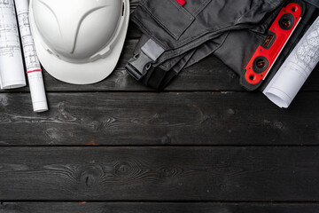 Construction worker unifrom, hardhat and blueprints on wooden background