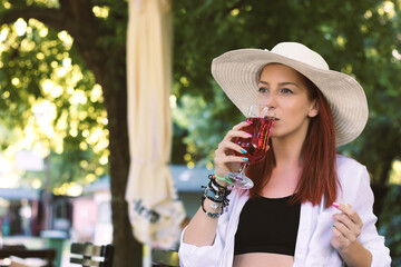 Redhead woman drinking summer cocktail outdoors.