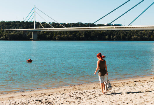 Rear View Of Redhead Woman Walking At The Beach In Summer Day.