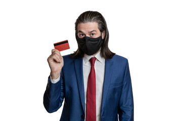 A man with long hair and a protective black mask, in a suit, white shirt and red tie with a credit card in his hands on a white background. 