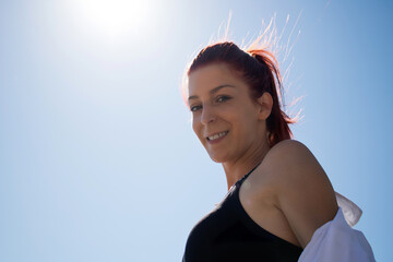 Below view of happy redhead woman against the sky.