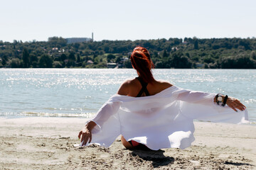 Back view of carefree woman with arms outstretched at the beach.