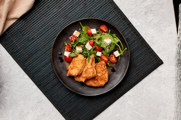 Fried chicken steaks in batter with a fresh salad of herbs, tomatoes and Feta cheese