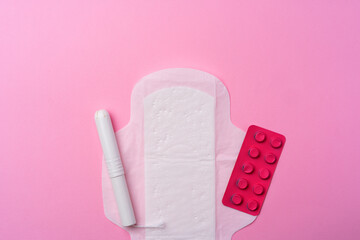 Сontraceptive pills, hygienic pads and tampons on pink background