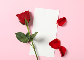 Blank greeting card, rose and petals on pink background, flat lay. Valentine's day celebration