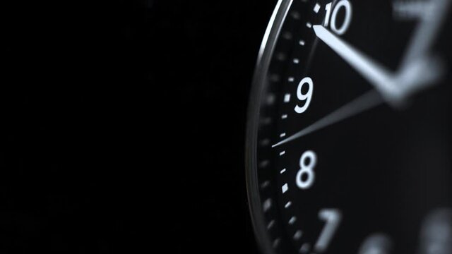 Watch with a second hand. Macro shooting. Black metal watch with white arrows on a black background.
