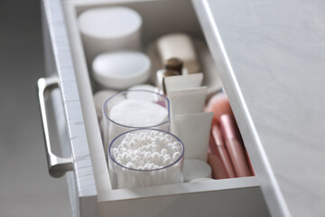 Fototapeta na wymiar Open cabinet drawer with cotton buds and pads indoors, closeup