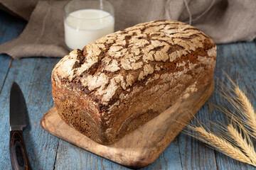 Rye bread with sunflower seeds on a serving board. Pieces of bread on a board with a glass of milk on a wooden rustic table. Healthy rye bread	