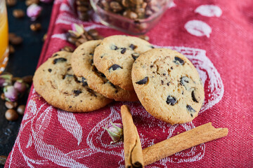 Chocolate chips cookies on a red tablecloth with cinnamons