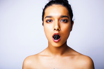 young pretty indian woman with dry fruit in mouth on white background