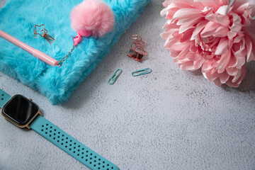 Fluffy diary with cute pink pen and some office supplies on a table. Pink dahlia flower in a corner