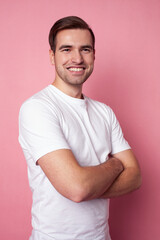 young caucasian guy in white t-shirt posing cheerful on pink background, lifestyle people concept