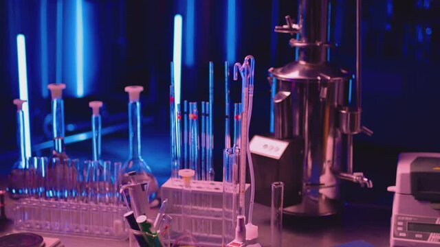 Medical or chemical development modern laboratory . Laboratory equipment , test tubes glasses on the table on background with blue lights . Dark room . Shot on ARRI ALEXA camera with dolly movement .