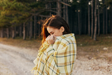 beautiful smiling woman with a plaid on her shoulders and forest in the background