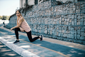 A sportswoman doing warm up exercises in urban exterior.