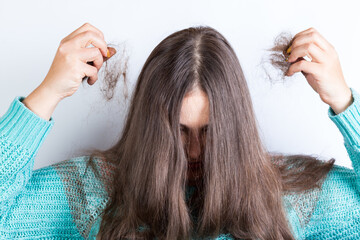 Fototapeta premium Woman holding bundles of hair. lost hair in hands.