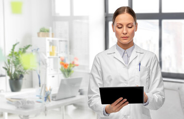 Fototapeta premium medicine, profession and healthcare concept - female doctor in white coat with tablet pc computer over medical office at hospital on background