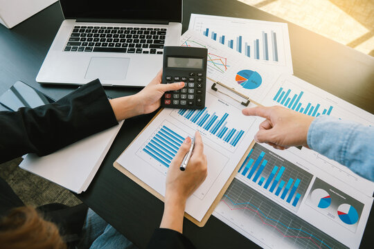 Businessmen use a calculator to calculate company financial statements for their colleagues, view and jointly solve problems within the company. Business finance and accounting concepts