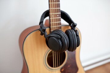 leisure, music and musical instruments concept - close up of acoustic guitar and headphones