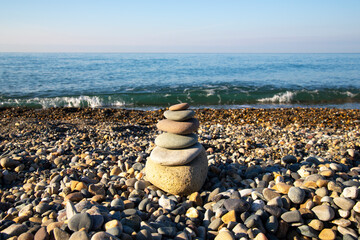 the concept of balance and harmony. stones on the beach in nature. A pyramid of stones on a beach of pebbles, in the background a blurred background of the sea and sky at dawn