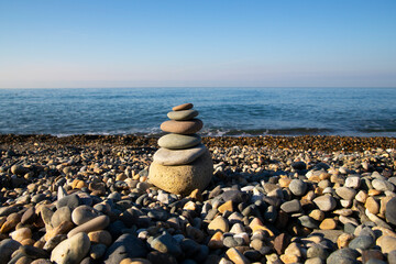 the concept of balance and harmony. stones on the beach in nature. A pyramid of stones on a beach of pebbles, in the background a blurred background of the sea and sky at dawn