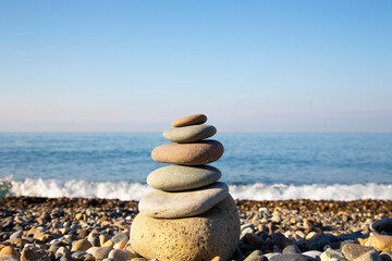 the concept of balance and harmony. stones on the beach in nature. A pyramid of stones on a beach of pebbles, in the background a blurred background of the sea and sky at dawn