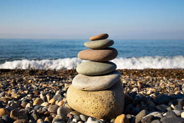 the concept of balance and harmony. stones on the beach in nature. A pyramid of stones on a beach of pebbles, in the background a blurred background of the sea and sky at dawn