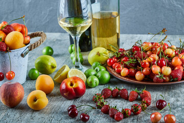 Two bottle and glass of wine on marble table with bunch of summer fresh fruits