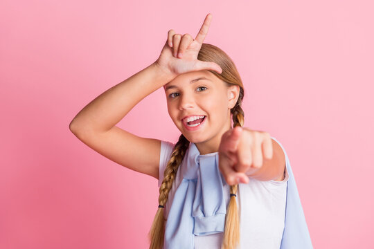 Photo portrait rude abusing little girl showing looser sign pointing finger at you isolated on pastel pink color background