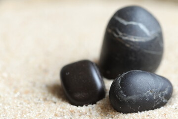Fototapeta na wymiar Three black stones in the sand.