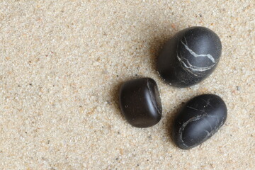 Fototapeta na wymiar Three black stones in the sand.