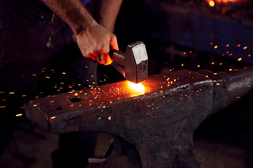 Close Up Of Male Blacksmith Hammering Metalwork On Anvil With Sparks