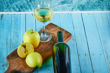 Apple slices on wooden cutting board with a glass of wine and bottle