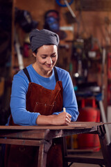 Female Blacksmith Wearing Headscarf Working On Design In Forge