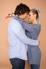 Beautiful romantic couple isolated on beige background. Attractive young woman and handsome man are hugging and smiling. Celebrating Saint Valentine's Day
